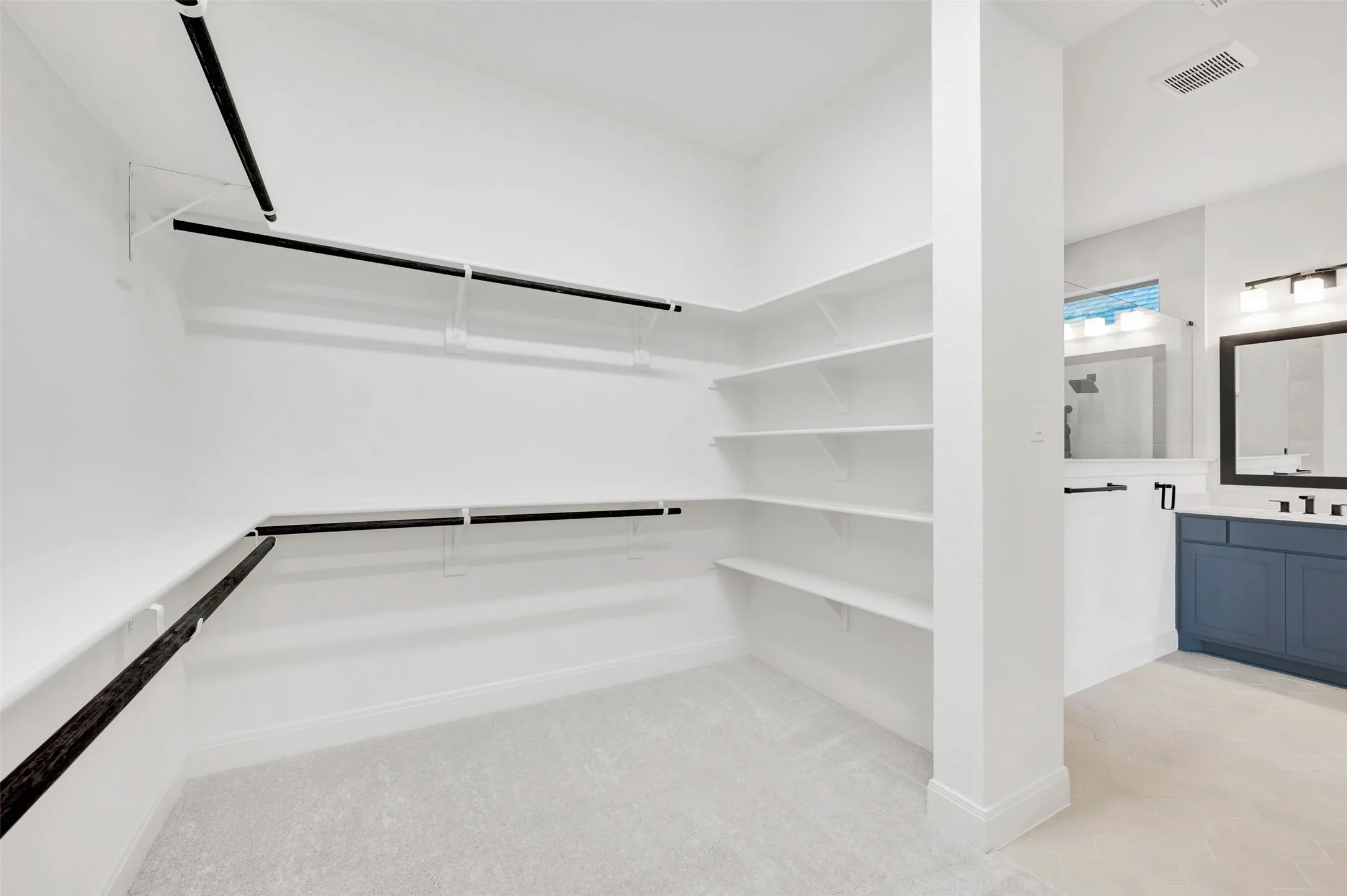 Spacious walk-in closet featuring white shelving and black hanging rods