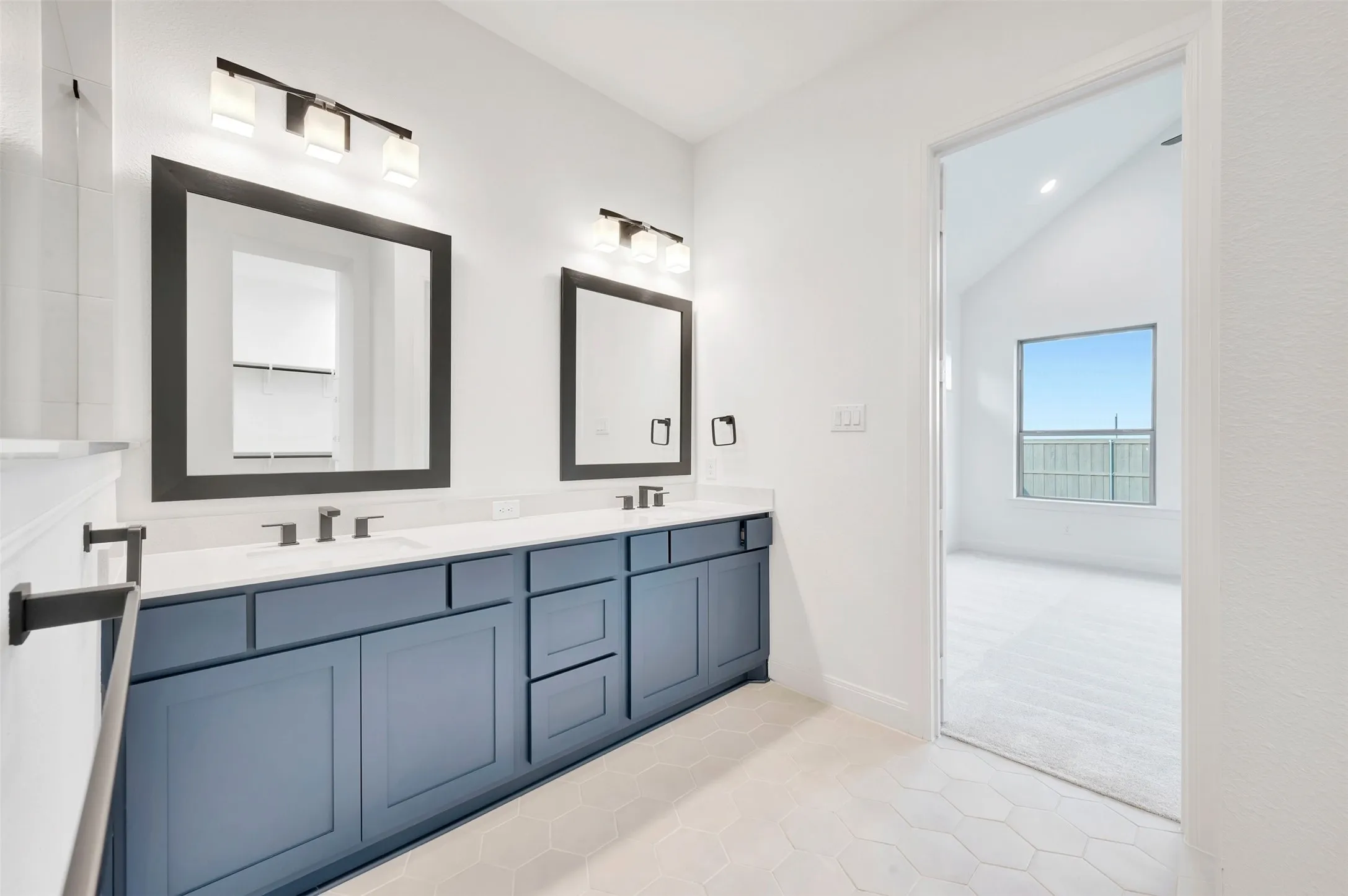 Dual vanity with blue cabinetry, undermount sinks, and wall-mounted light fixtures