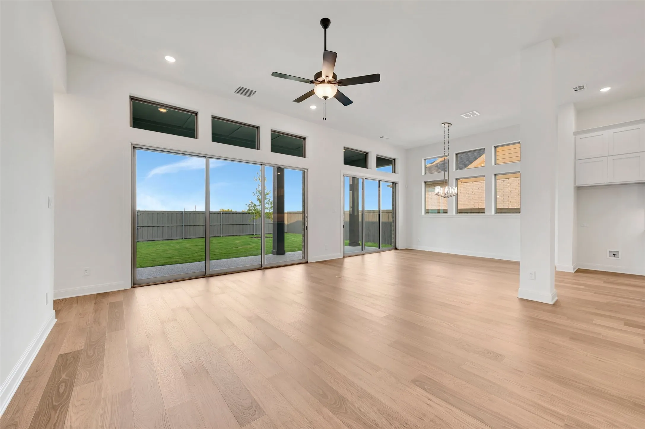 Expansive open-concept room featuring light wood-finish flooring, a contemporary ceiling fan, and recessed lighting
