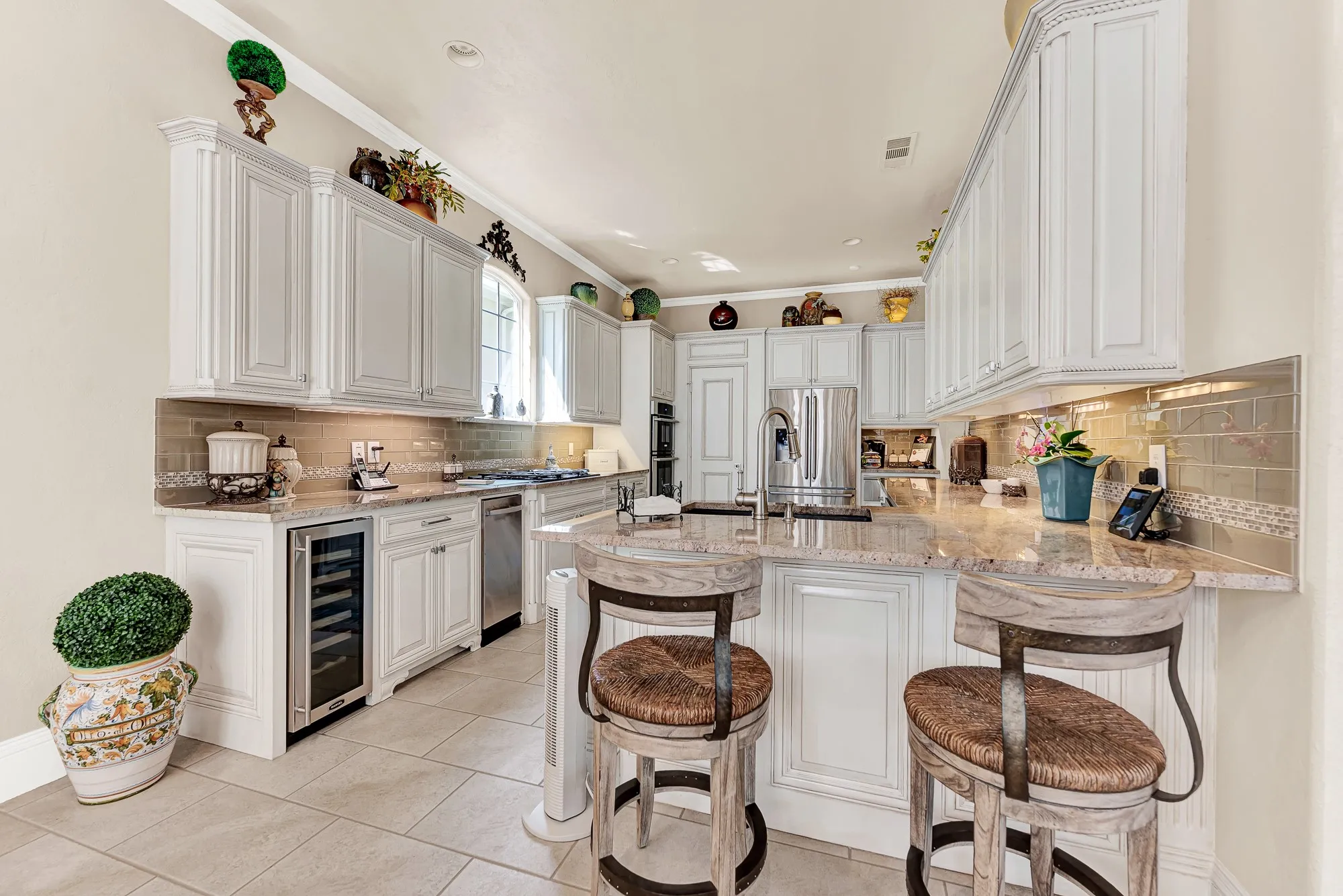 Refined white cabinetry, rich granite countertops, glossy subway tile, and a built-in wine cooler highlight this functional kitchen island setup. You will love pulling up a seat for casual weeknight meals or serving drinks to friends during weekend parties.