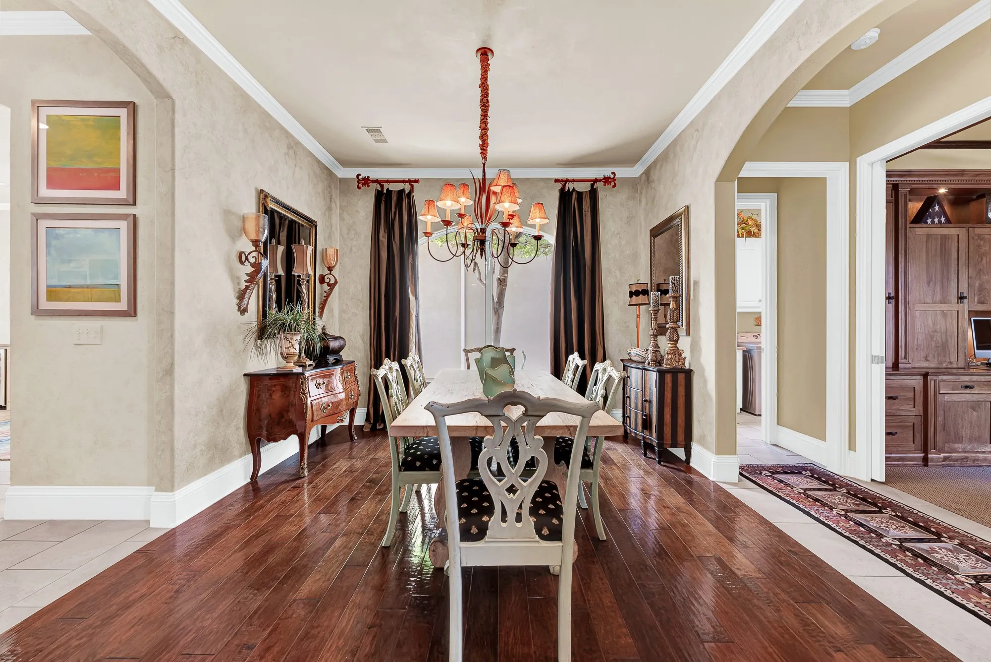 Rich hardwood floors, detailed crown molding, textured walls, and a warm multi-light chandelier set a sophisticated scene in this formal dining room. You will love gathering here with family and friends for unforgettable holiday dinners and celebratory meals.