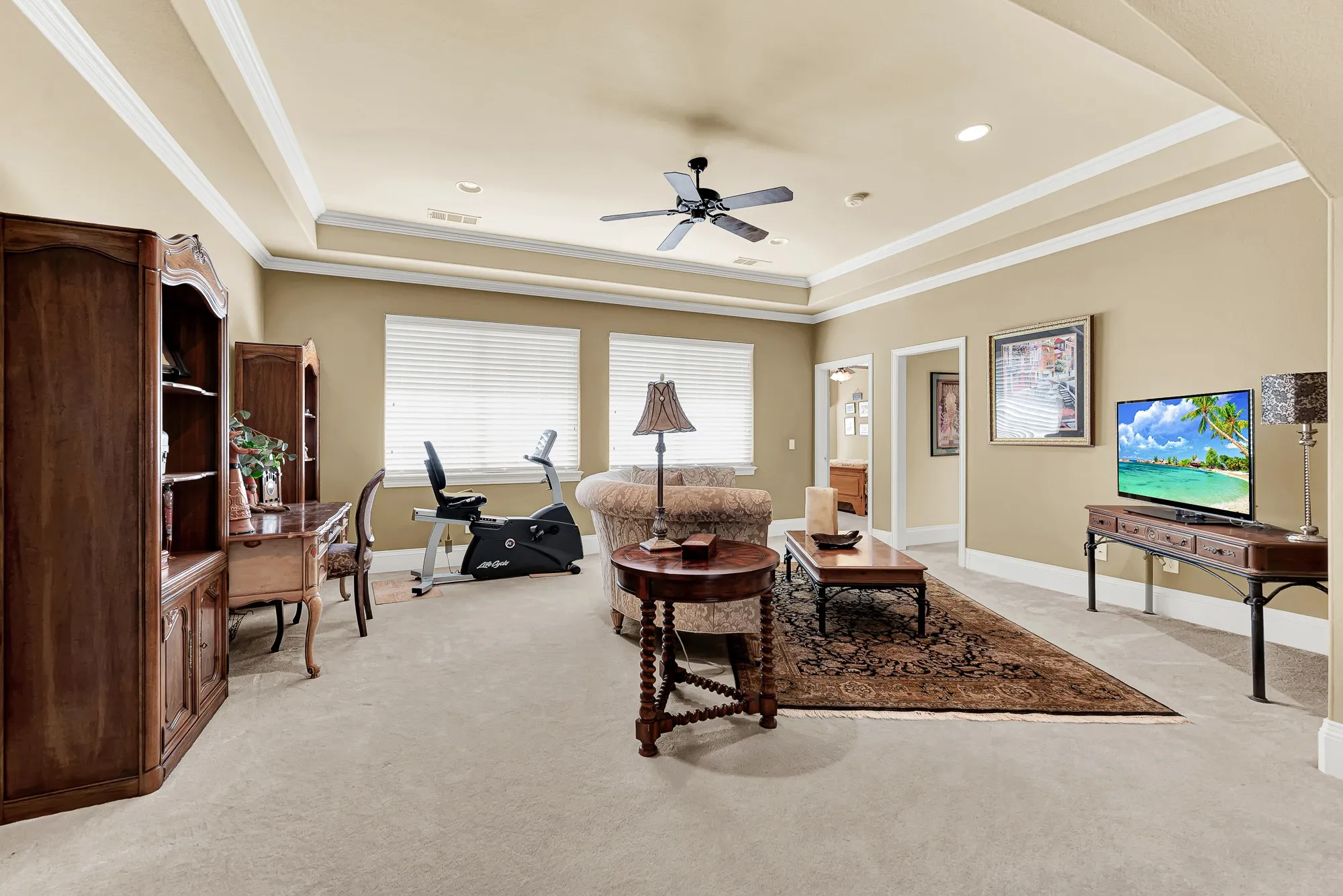 Plush carpeting, tiered tray ceilings with crown molding, and twin shuttered windows create a warm upper-level retreat step from two guest bedrooms. It is the perfect flexible zone for kids to play games or guests to enjoy their own quiet living space.