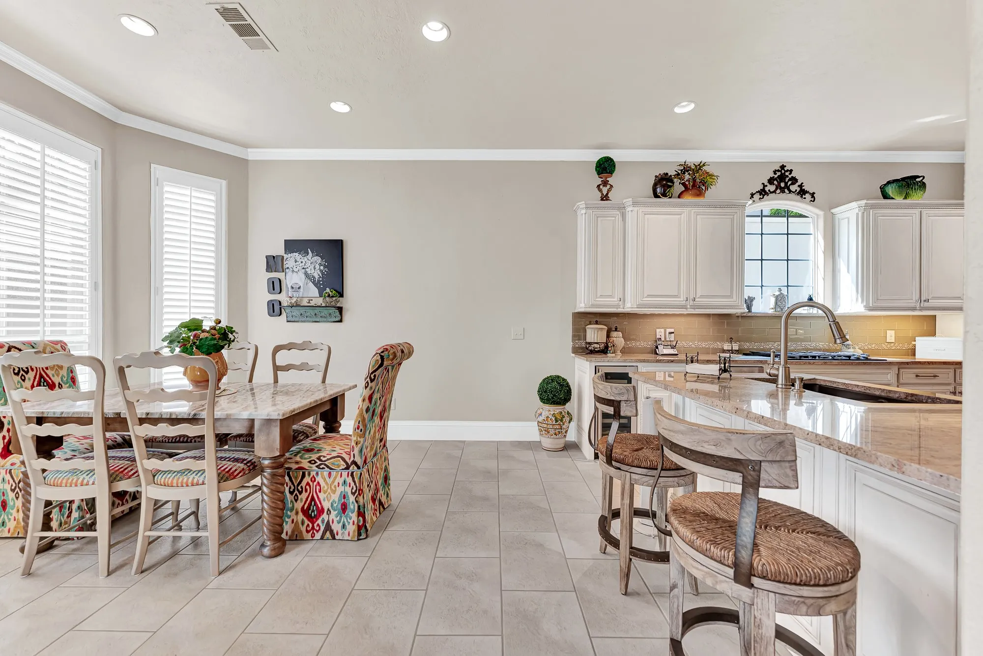 Continuous tile flooring effortlessly connects the eat-in dining area to the kitchen island and surrounding prep counters. This smooth layout makes serving casual weeknight dinners or chatting with guests while cooking a total breez