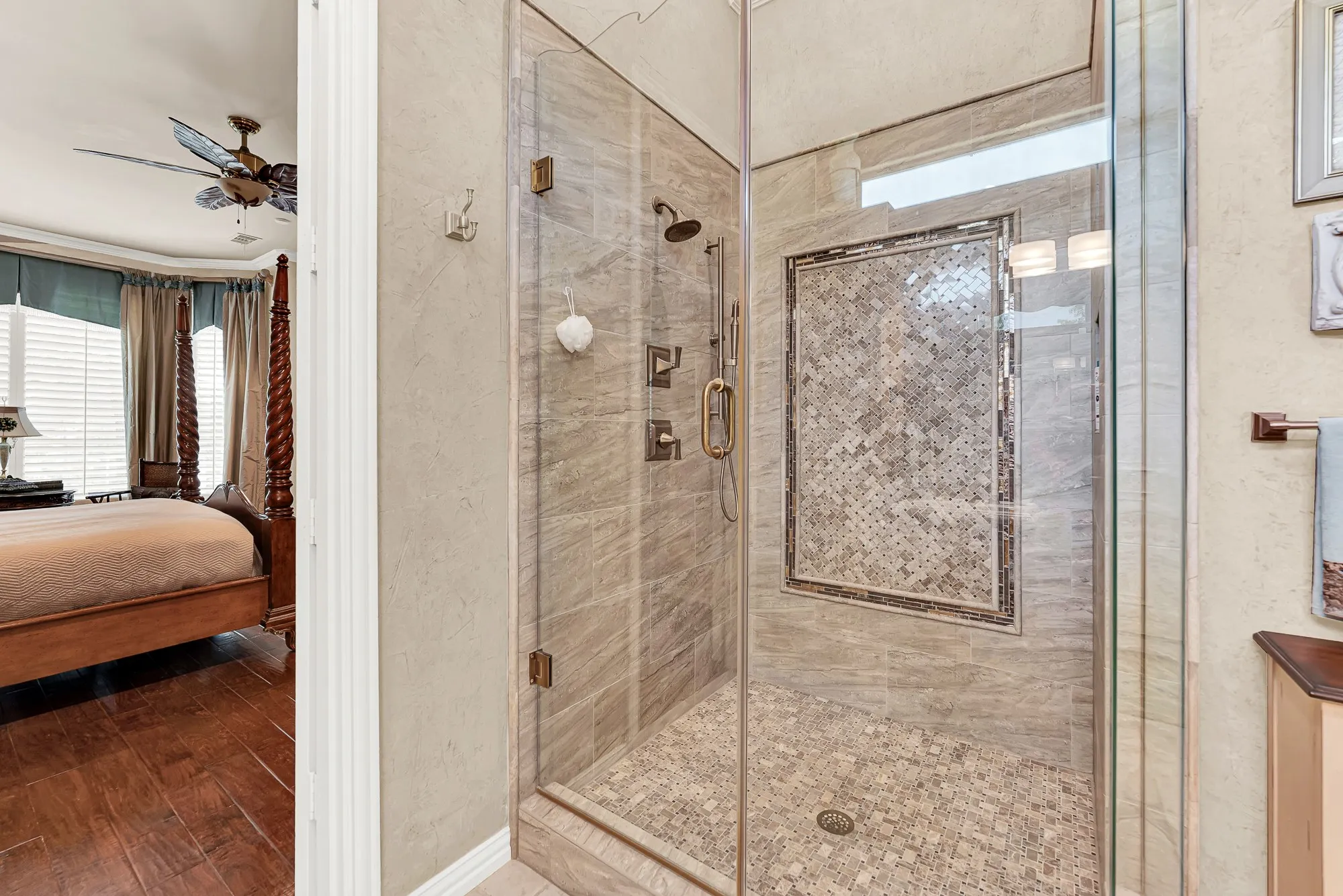 Seamless glass doors reveal a custom walk-in shower complete with intricate tile accents and dual shower heads just steps from the bedroom. Step in for a quick, invigorating rinse to start your day energized and refreshed.