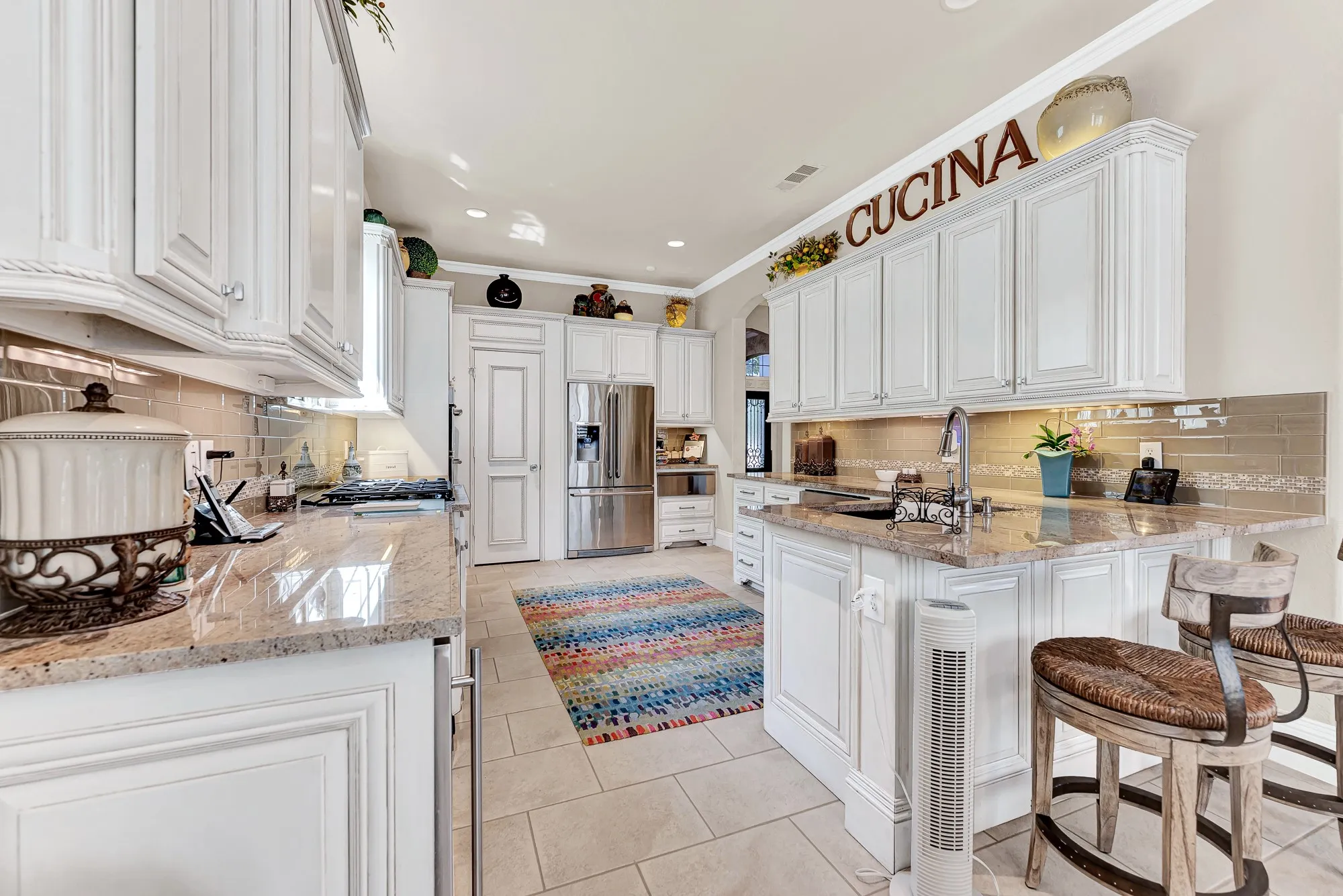 Under-cabinet lighting illuminates expansive prep surfaces, framed by classic panel cabinetry and stainless steel appliances stretching toward the pantry. Cooking everyday dinners becomes a joy in this brightly lit, beautifully organized culinary space.