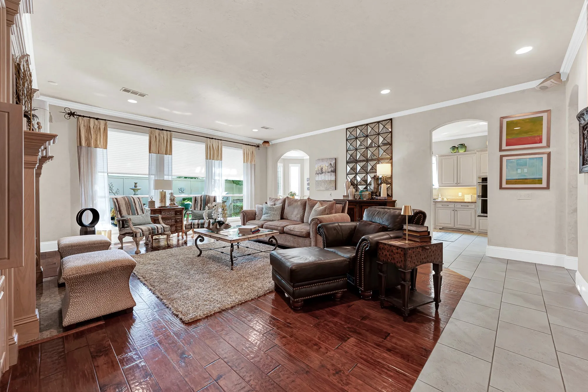 Tall rear windows frame inviting patio views while open archways connect the living space directly to the kitchen. Sunlight fills the room, making it a peaceful spot to relax with your morning coffee while enjoying sightlines to the backyard.