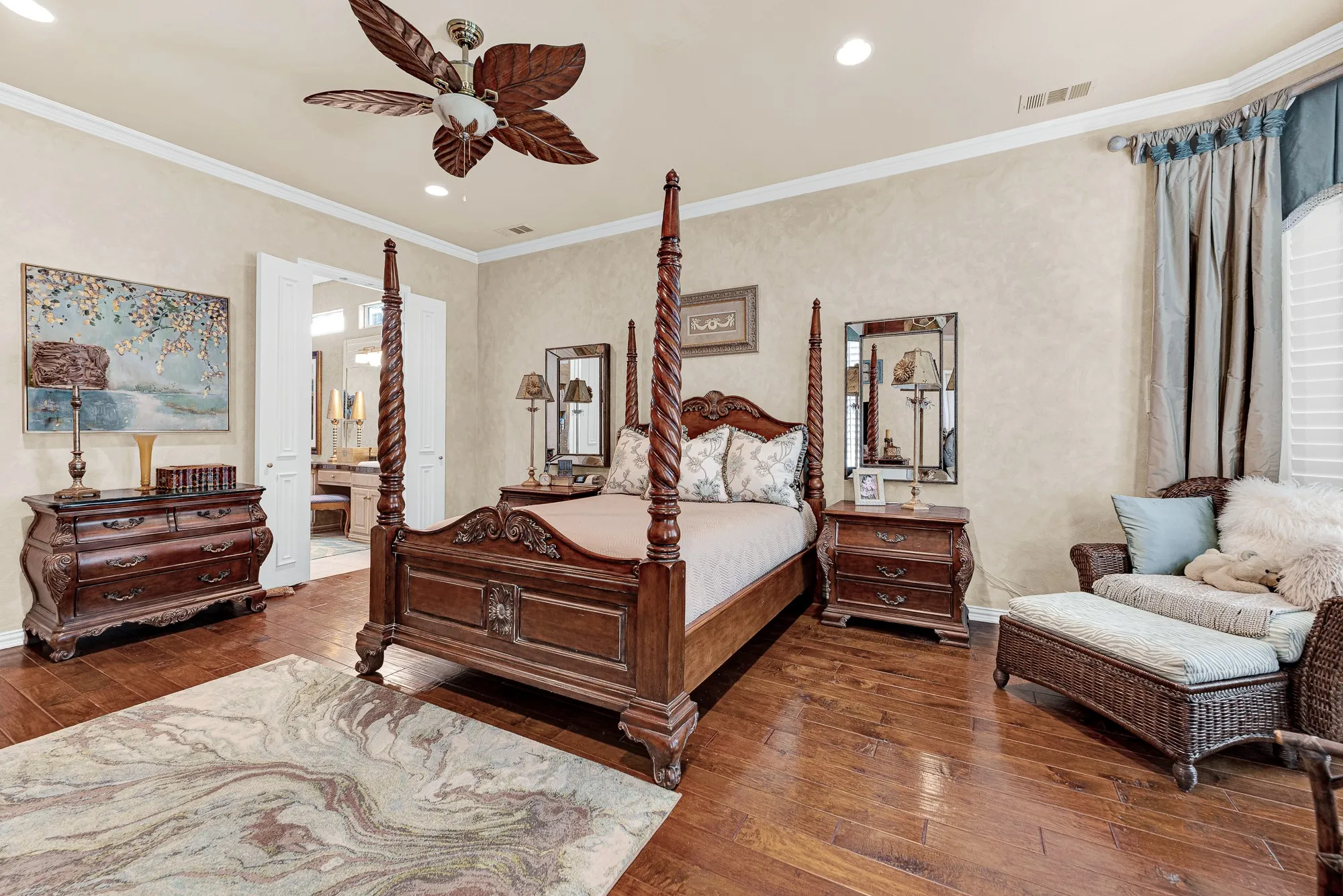 Polished wood flooring extends beneath warm recessed lighting, while double French doors open directly into the private ensuite bath. Resting here feels like a true spa-like escape, offering complete privacy and quiet comfort at the end of every day.