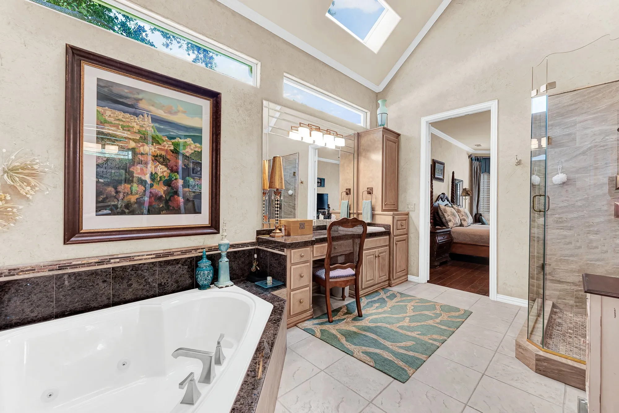High transom windows and skylights wash tile floors in light across the built-in vanity station and walk-in shower entrance. Starting your daily routine in this sunlit atmosphere keeps mornings bright and refreshing.