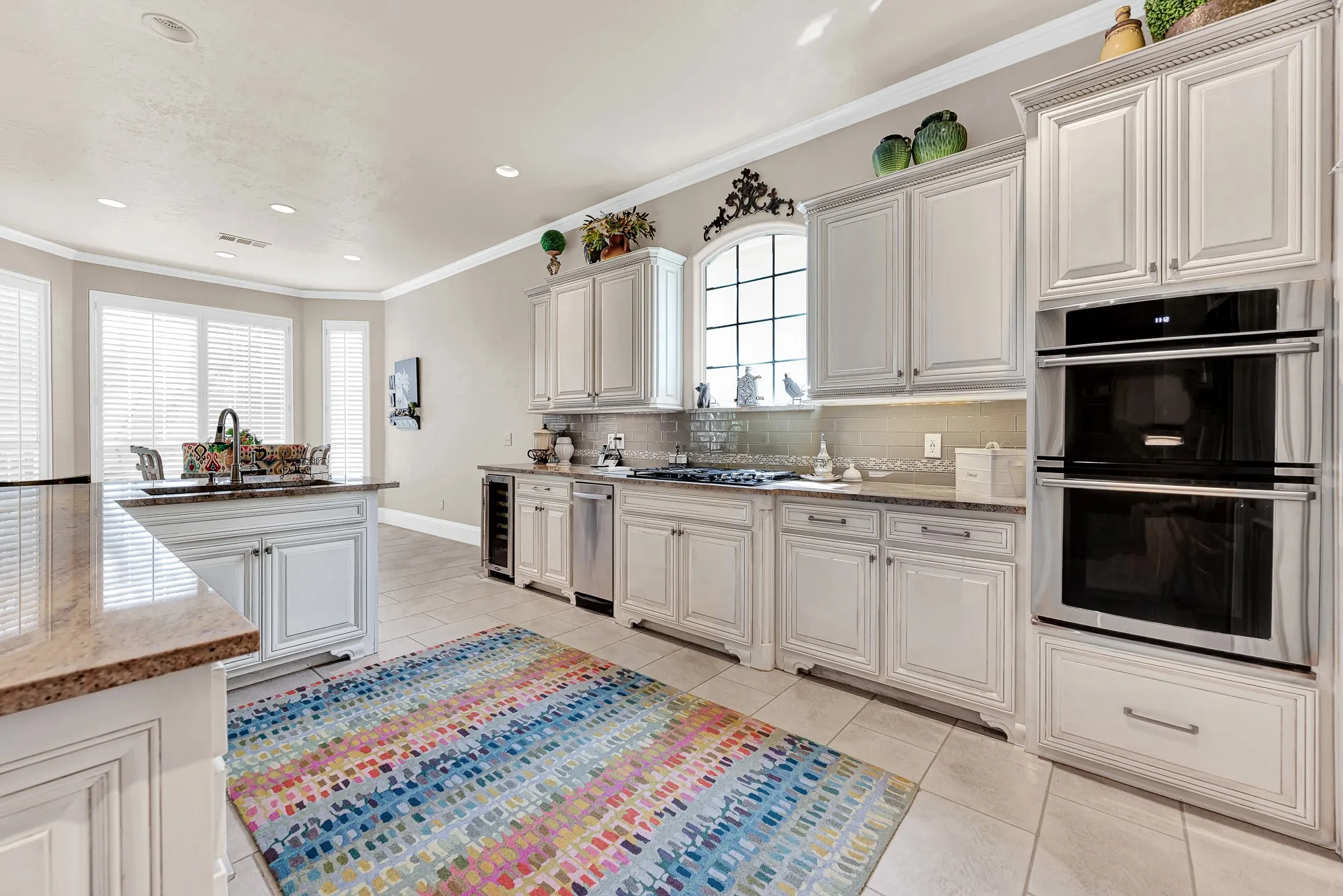A double wall oven, gas cooktop, arched accent window, and extended breakfast nook bay area complete this spacious kitchen setup. You will enjoy whipping up holiday feasts with ease while natural light pours in from the surrounding windows.
