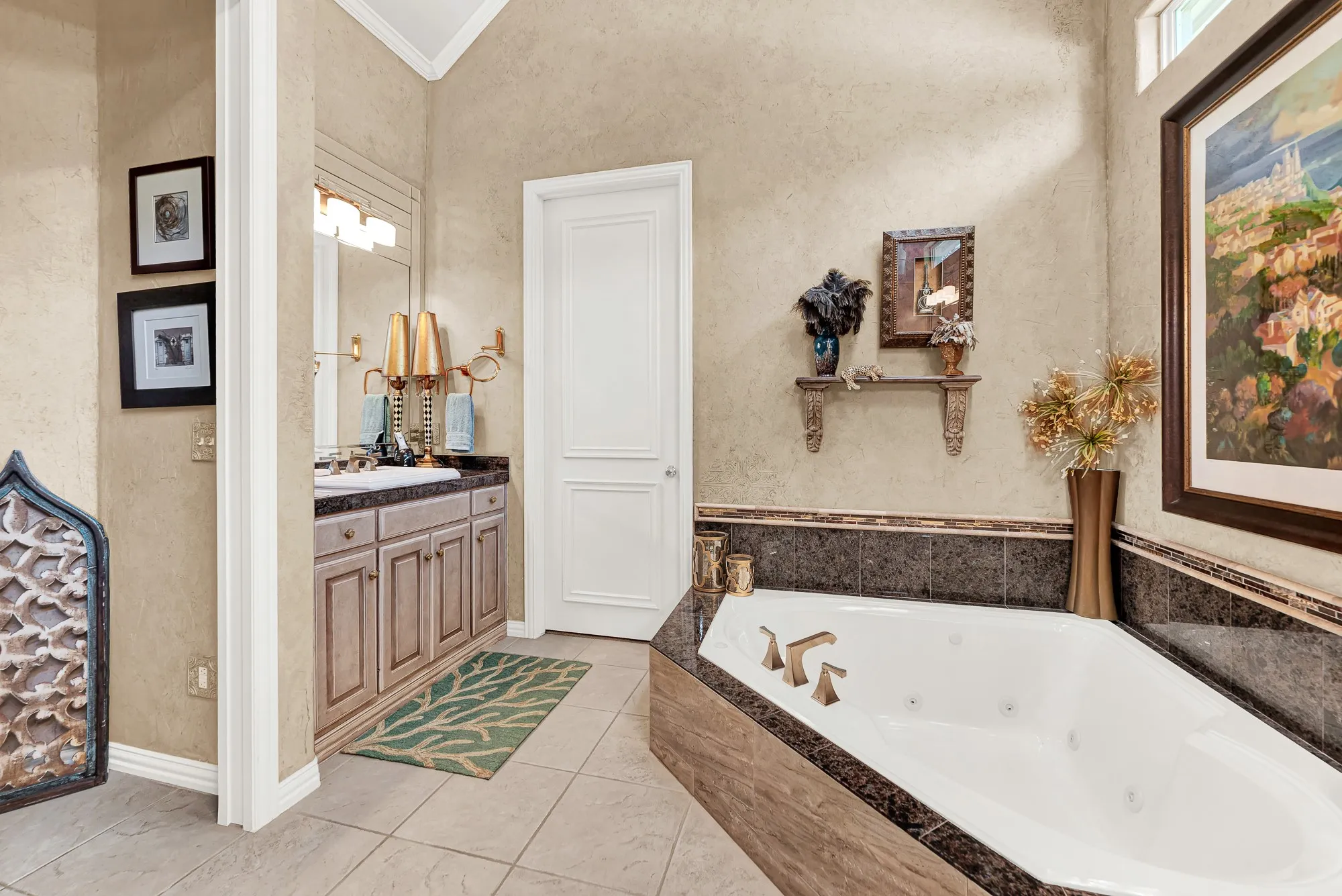 A dark granite surround accents the deep soaking tub, situated alongside a separate vanity station and neutral tile floor. Imagine lighting a few candles and relaxing in complete peace in this quiet retreat.