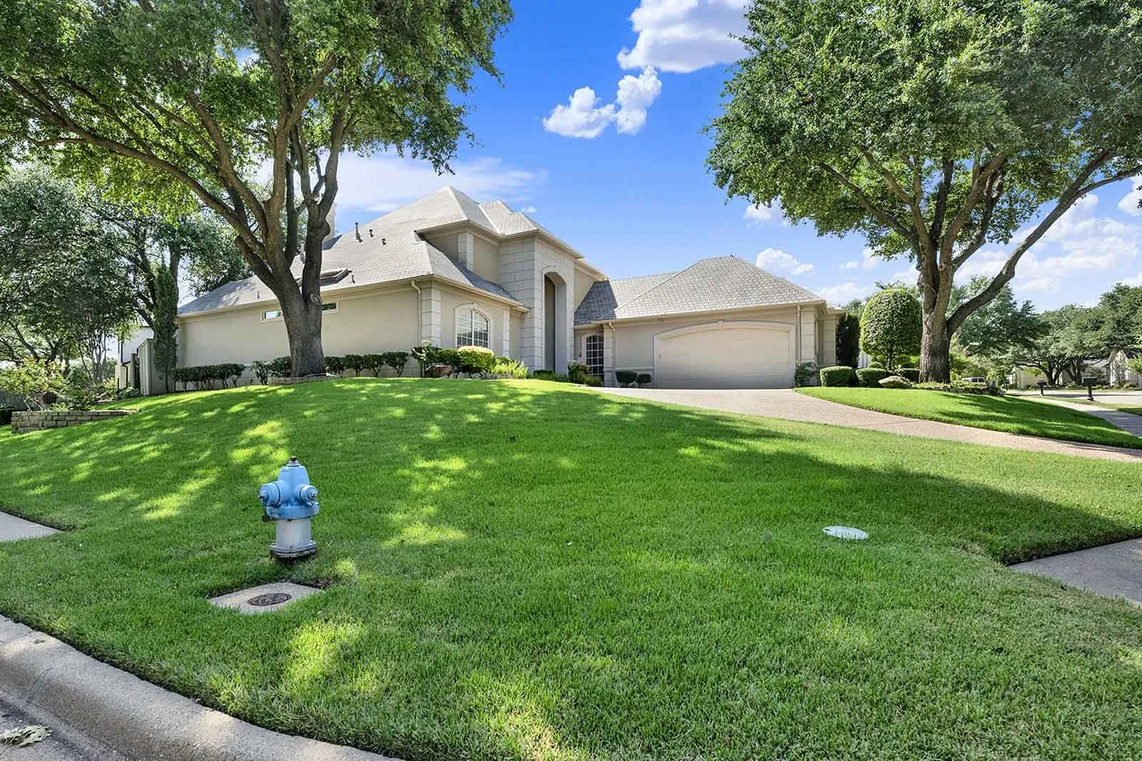 An expansive manicured lawn wraps around this desirable corner lot, framed by towering shade trees and a wide driveway entrance. You will love the exceptional curb appeal and extra outdoor elbow room this spacious lot provides for everyday living.