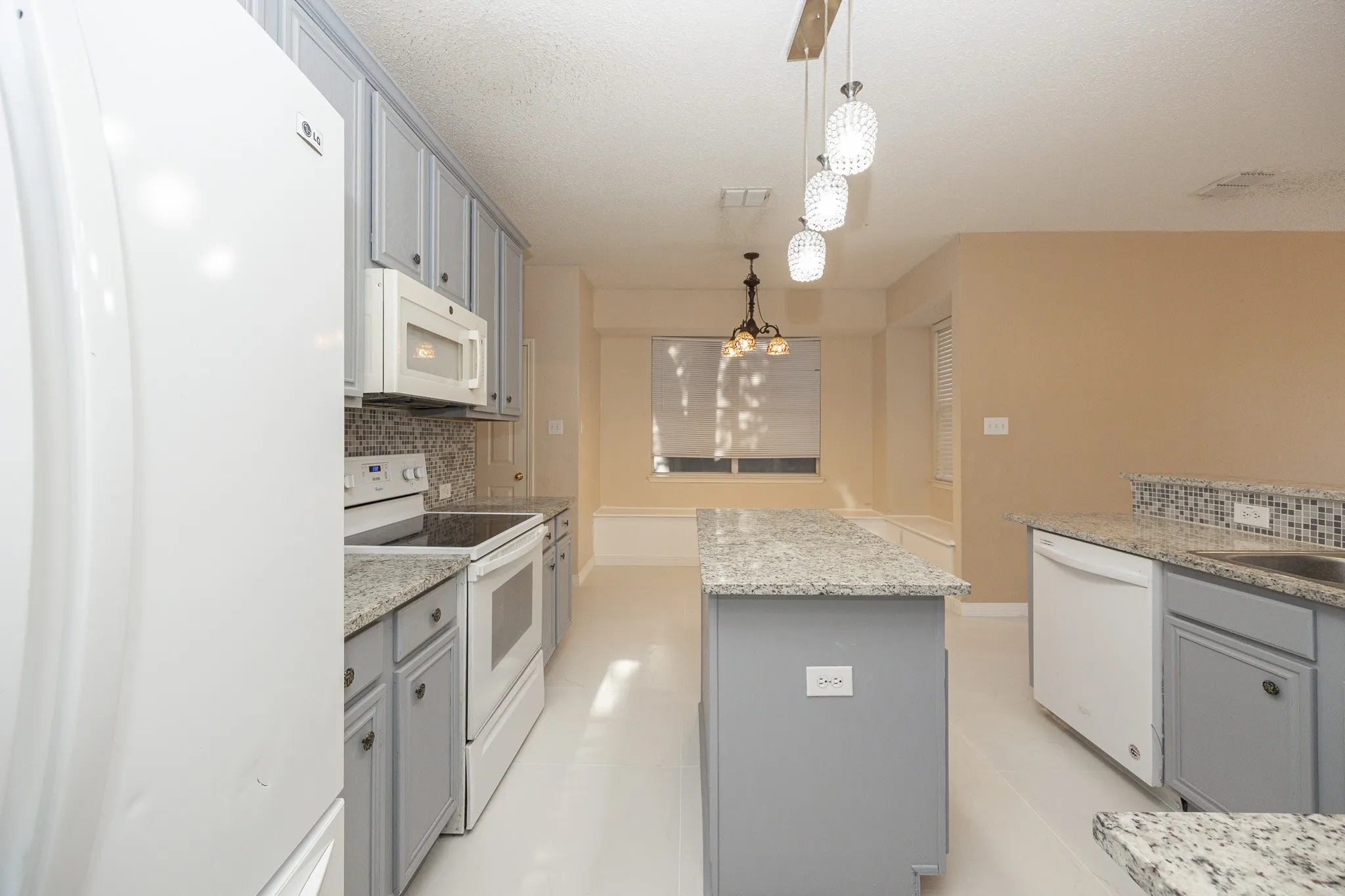 Kitchen featuring white appliances, gray cabinetry, granite countertops, and mosaic tile backsplash