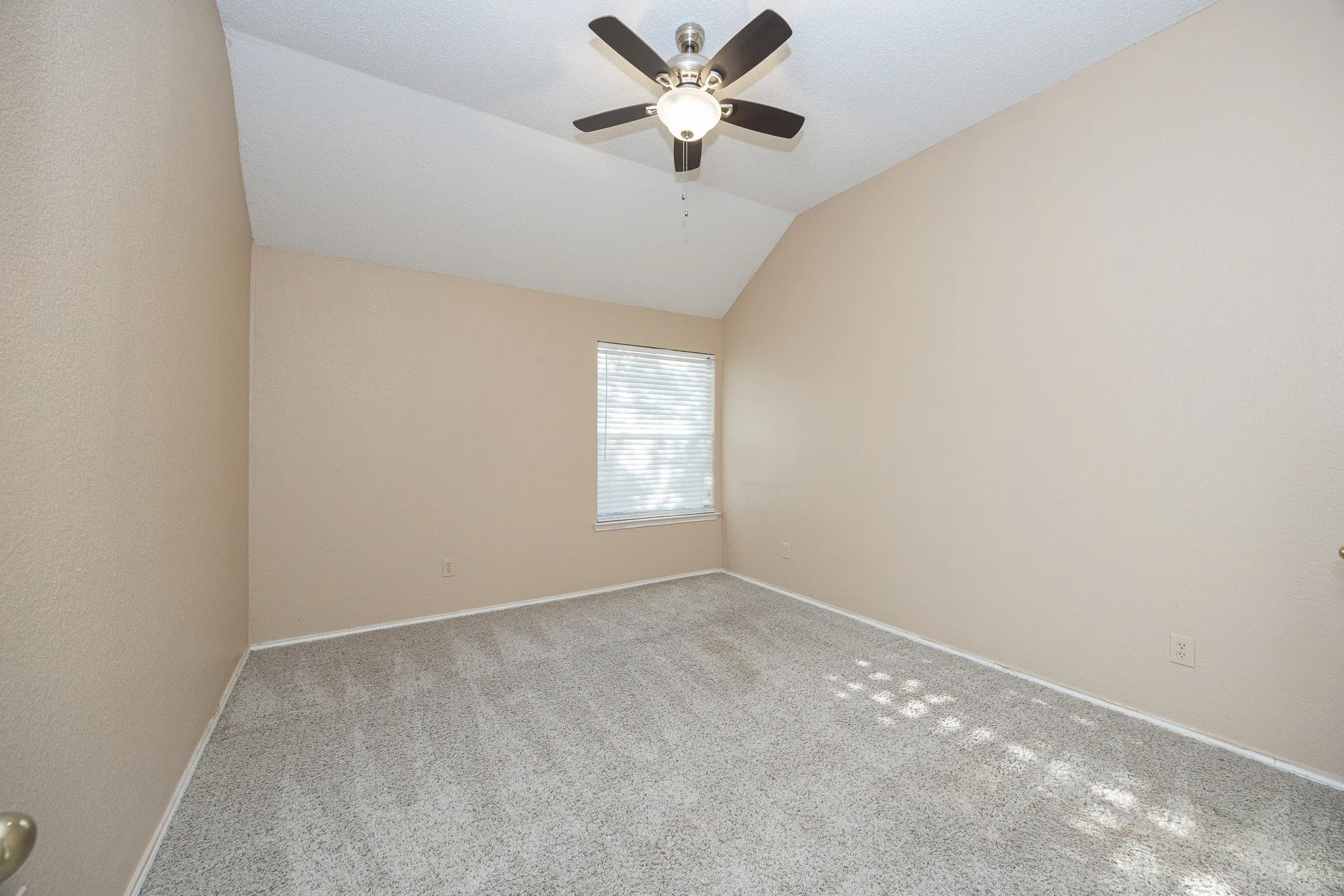 Vaulted ceiling with a ceiling fan, neutral carpet flooring, and a single window with blinds
