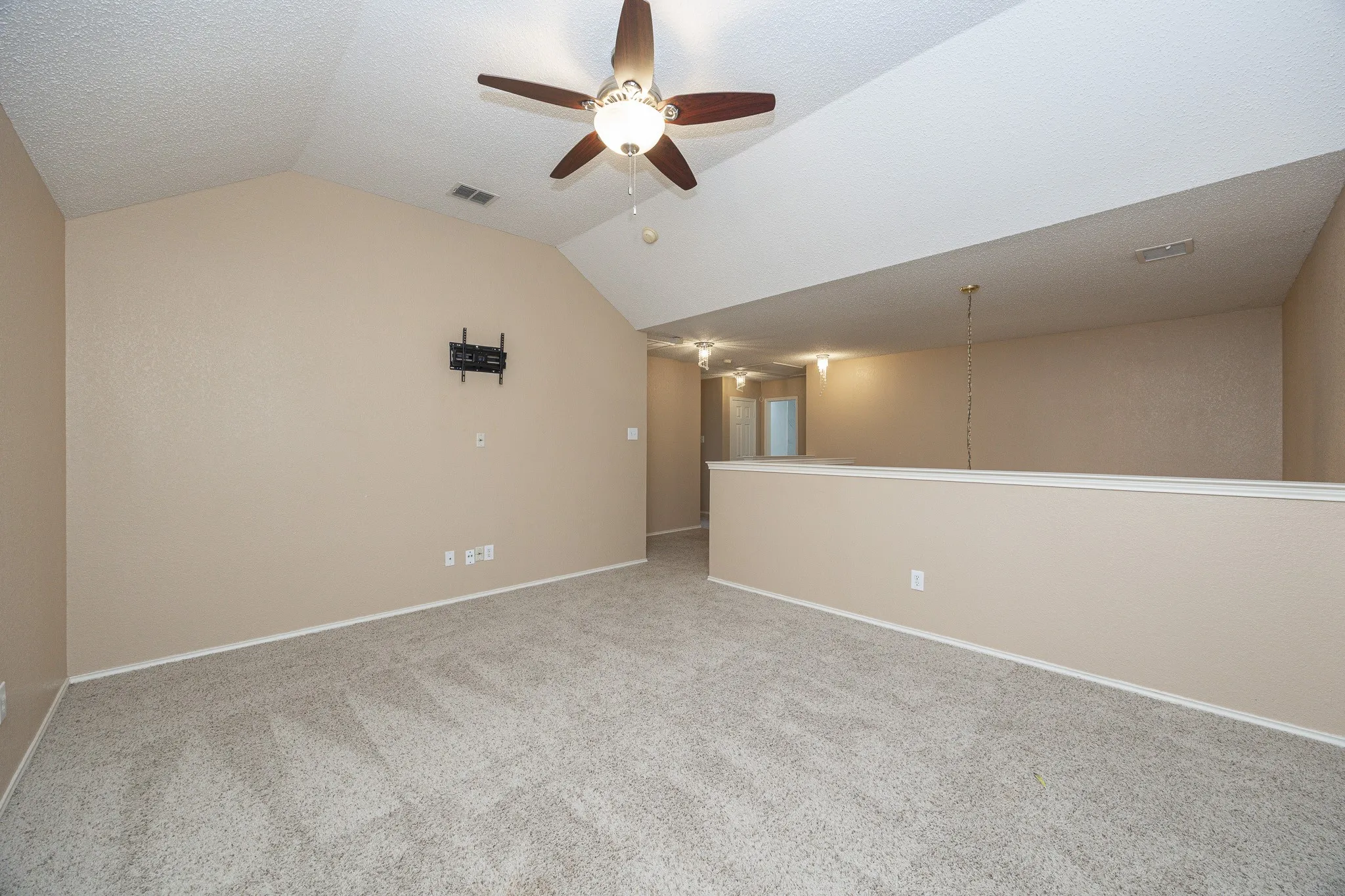Vaulted ceiling, ceiling fan, neutral wall paint, carpet flooring, interior railing