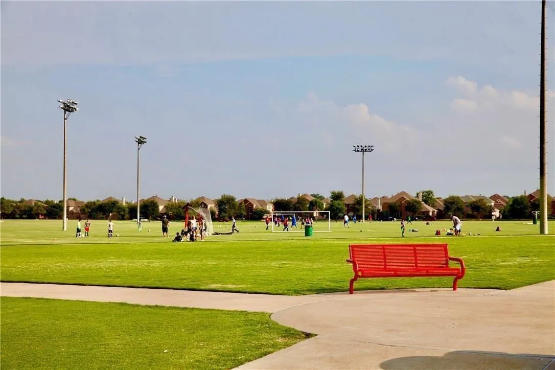 Expansive green space featuring a large field, integrated pathways, and permanent lighting fixtures