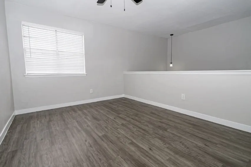 Wood-finish flooring, white wall trim, and a ceiling-mounted light fixture
