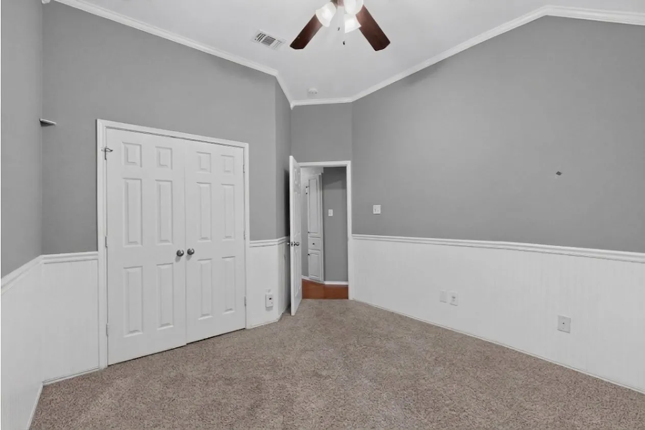 Vaulted ceiling with a ceiling fan, plush carpet flooring, beadboard wainscoting, and a paneled closet door