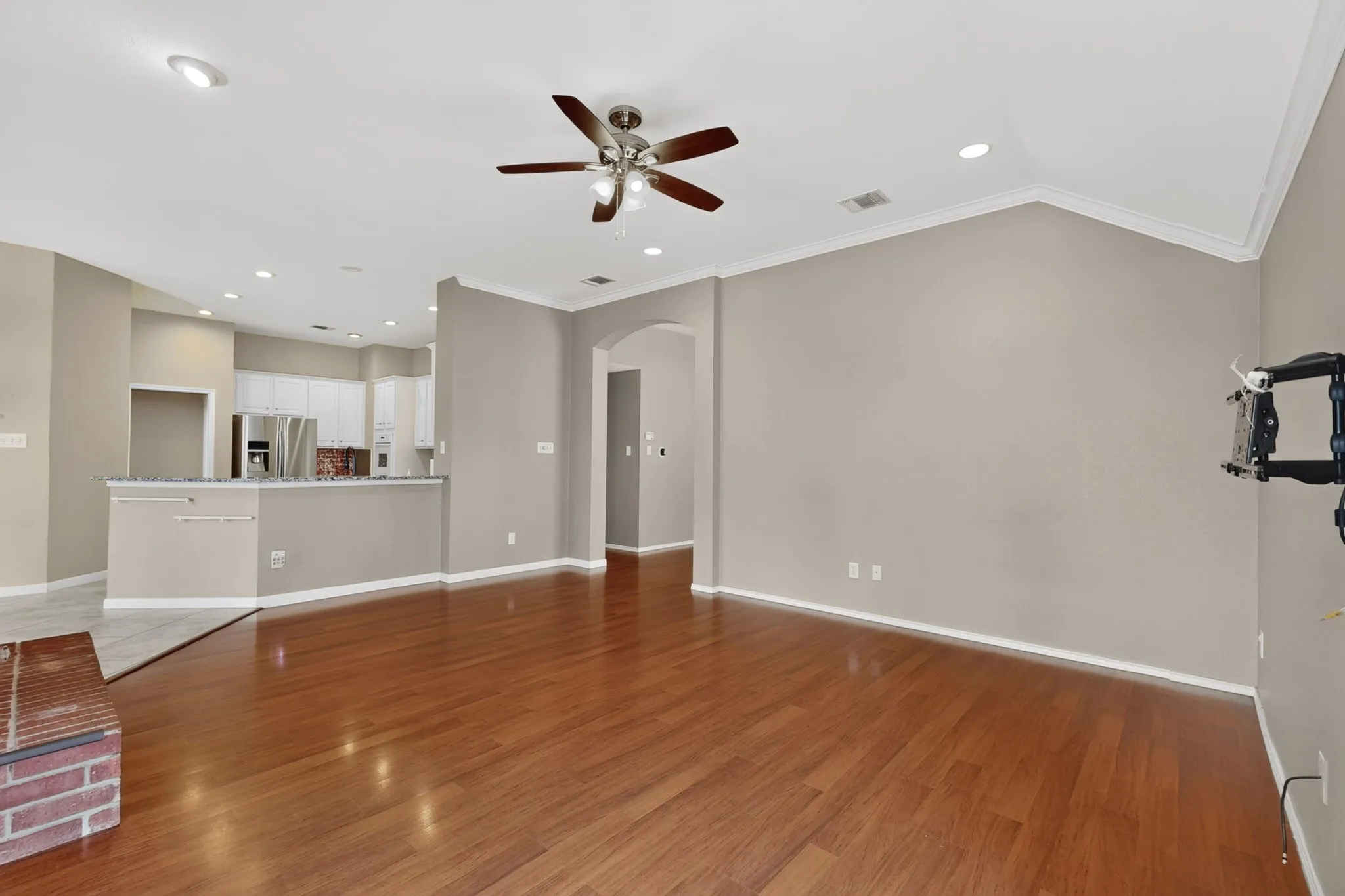 Hardwood flooring, recessed lighting, ceiling fan, vaulted ceiling, and an arched doorway