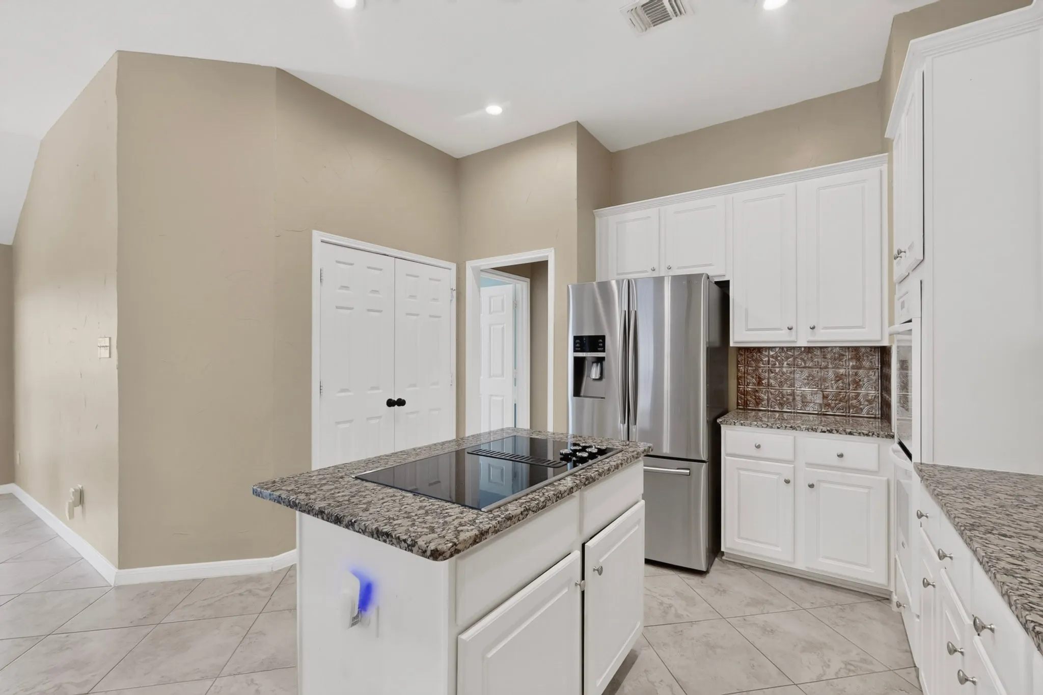 Kitchen featuring white cabinetry, granite countertops, stainless steel appliances, a tiled backsplash, and light-toned floor tiling