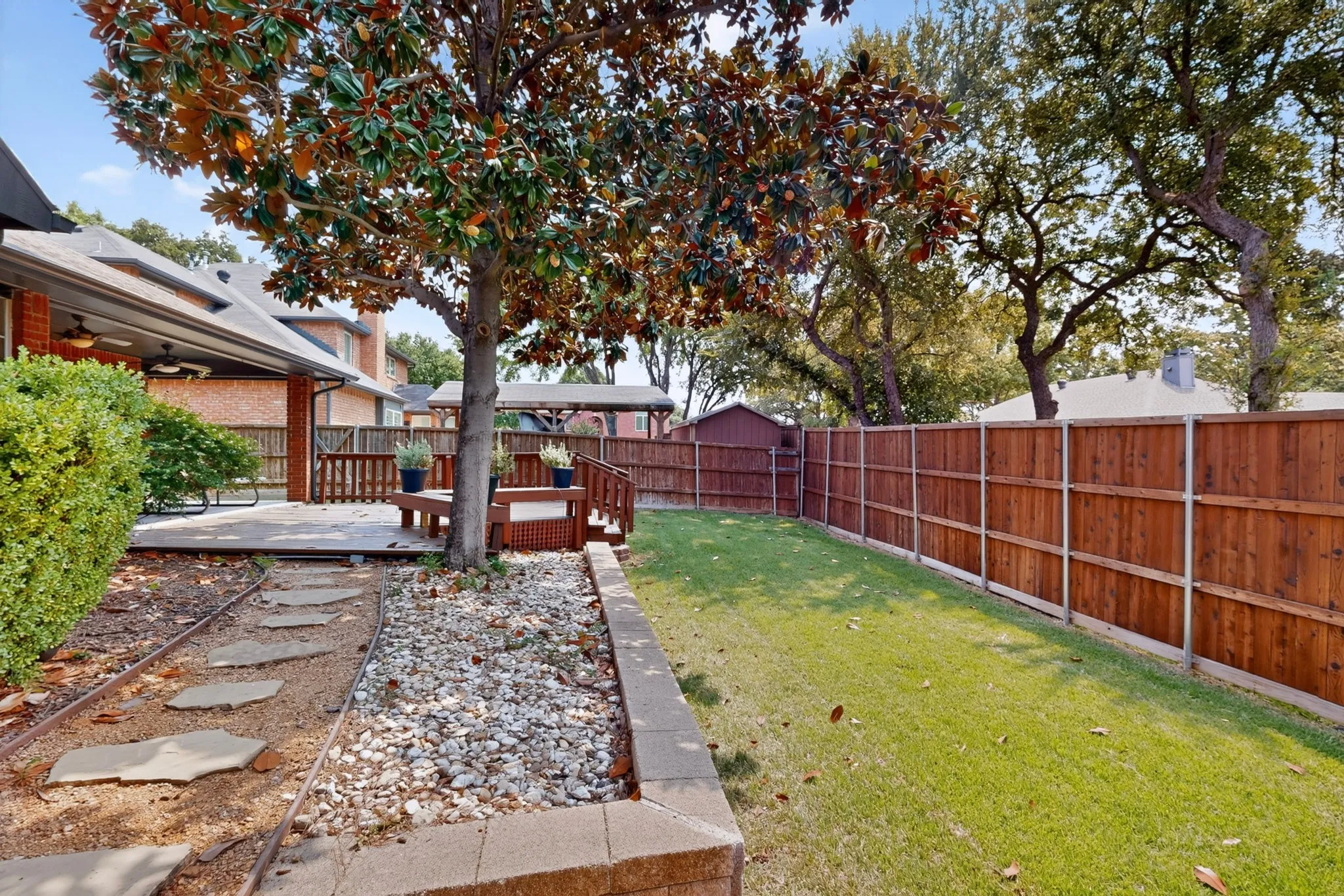 Expansive backyard featuring a manicured lawn, wood fencing, and a multi-level wooden deck