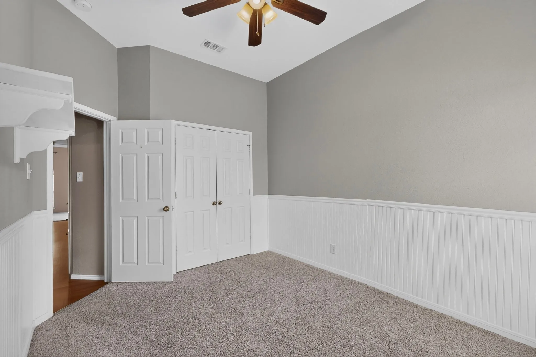 Vaulted ceiling, ceiling fan, carpet flooring, beadboard wainscoting, and double-door closet