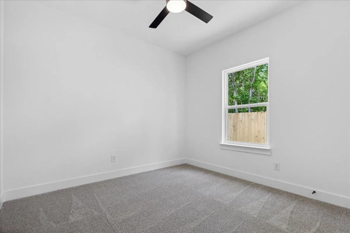 Neutral wall color, grey carpeting, ceiling fan, and window