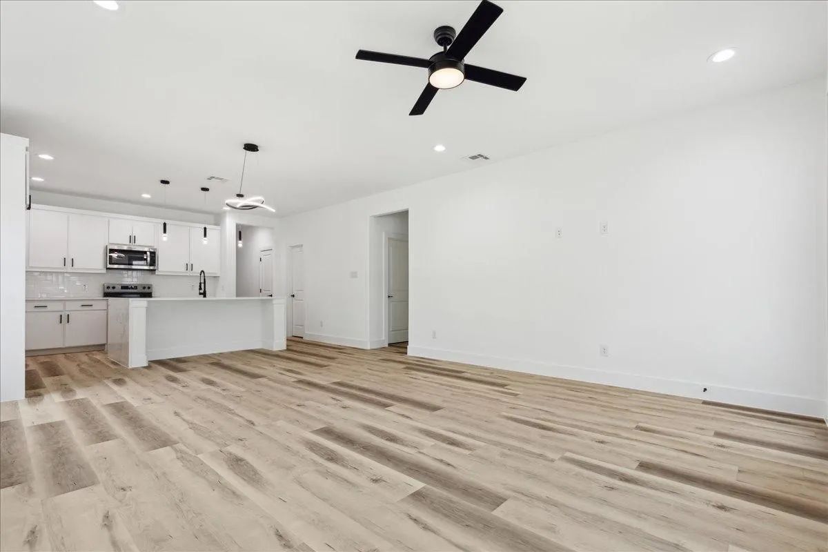 Open-concept living area with wood-finish flooring, recessed lighting, and a ceiling fan