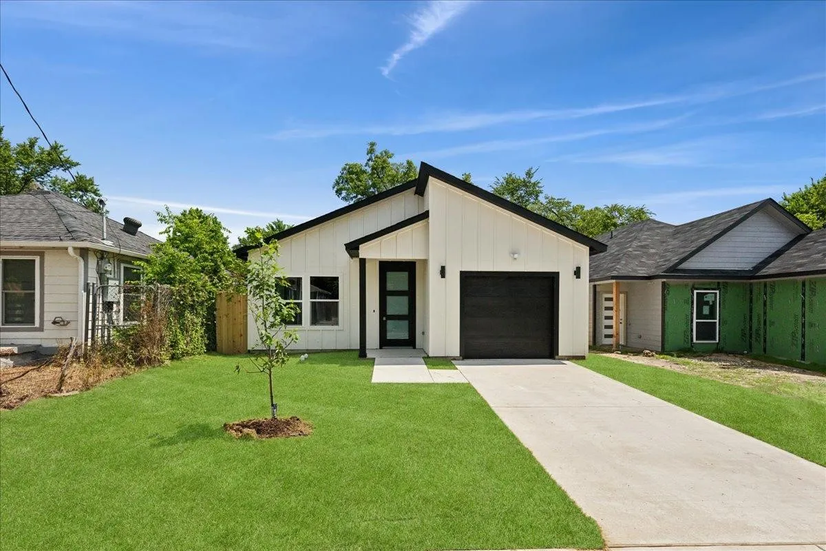 Modern exterior with white vertical siding, a black garage door, and a contrasting black roofline