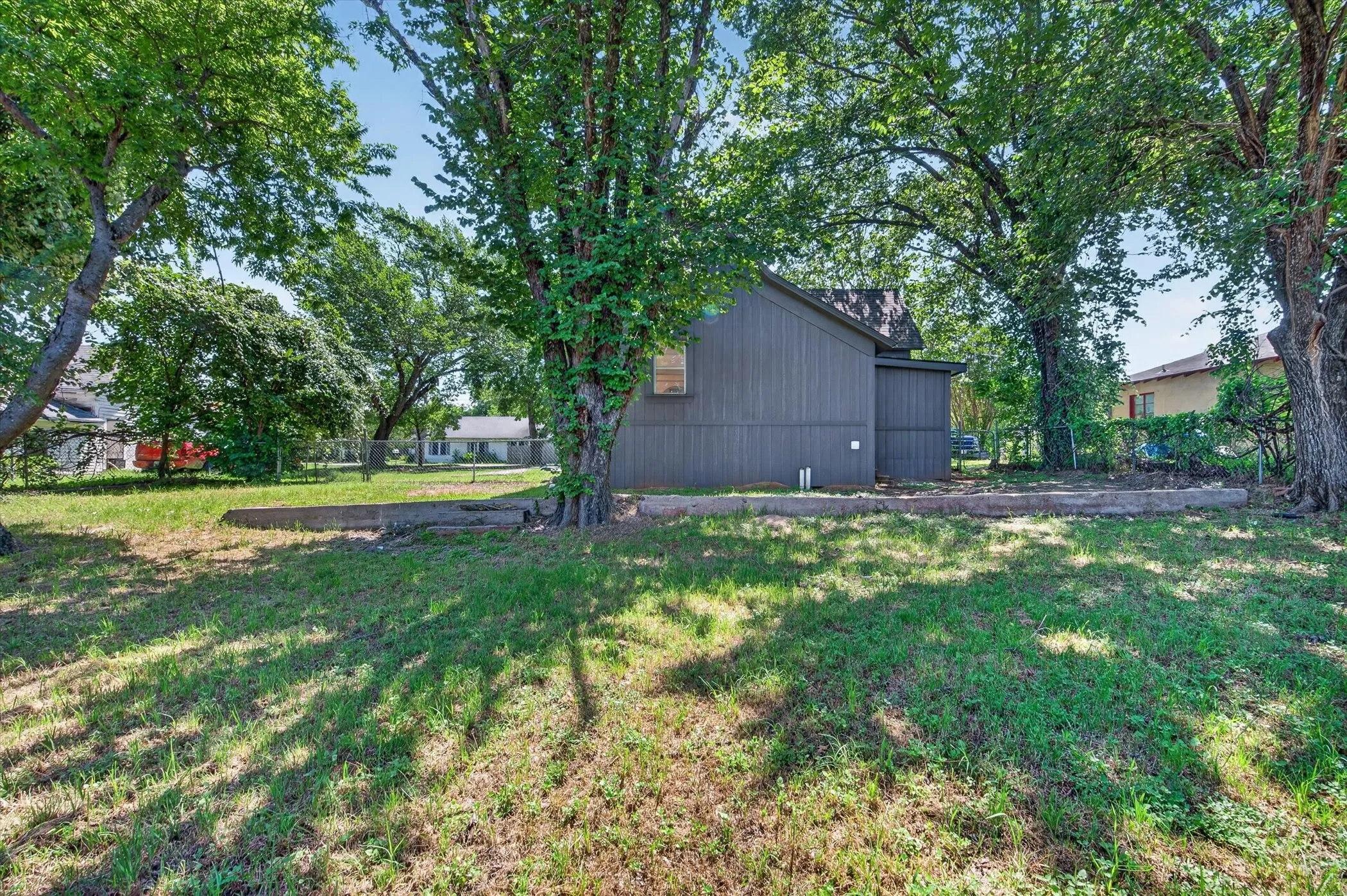Expansive grassy yard featuring mature trees providing ample shade