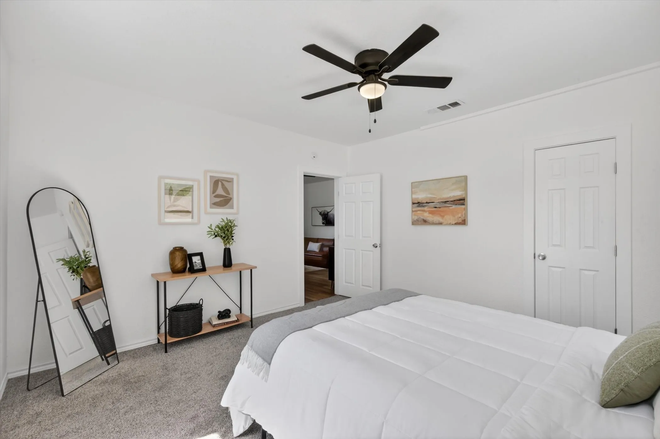 White walls complement gray carpeting throughout this room, featuring a dark ceiling fan with integrated lighting and two paneled​​‌​​​​‌​​‌‌​‌‌​​​‌‌​‌​‌​‌​​​‌​​ doors