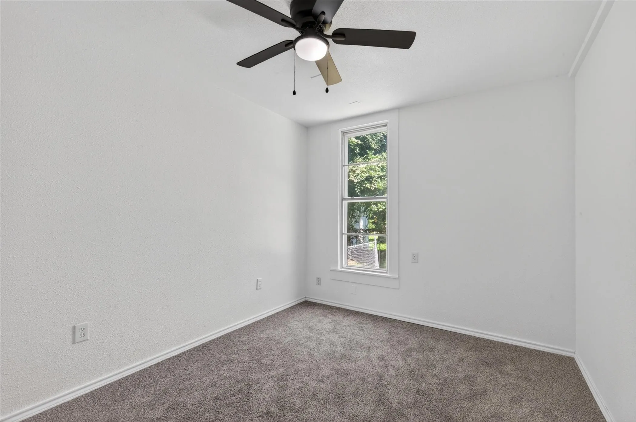 Carpeted room with a ceiling fan featuring integrated lighting, a single window, white walls, and white trim