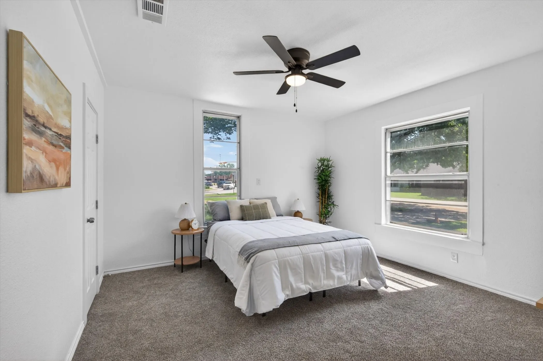 Carpeted room featuring a ceiling fan with integrated lighting, white walls, and two large windows with white trim