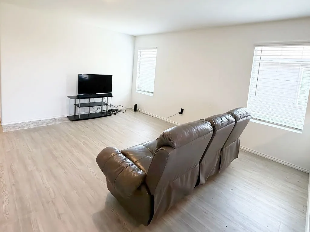 Wood-finish flooring with white walls and natural light from multiple windows