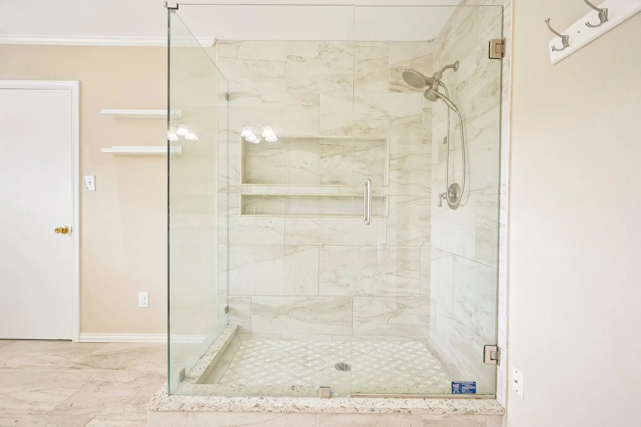 Glass-enclosed shower with large format tile surround and dual recessed shelves