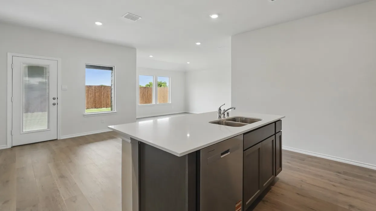 Kitchen island with a dual basin sink, stainless steel dishwasher, and dark wood-finish cabinetry