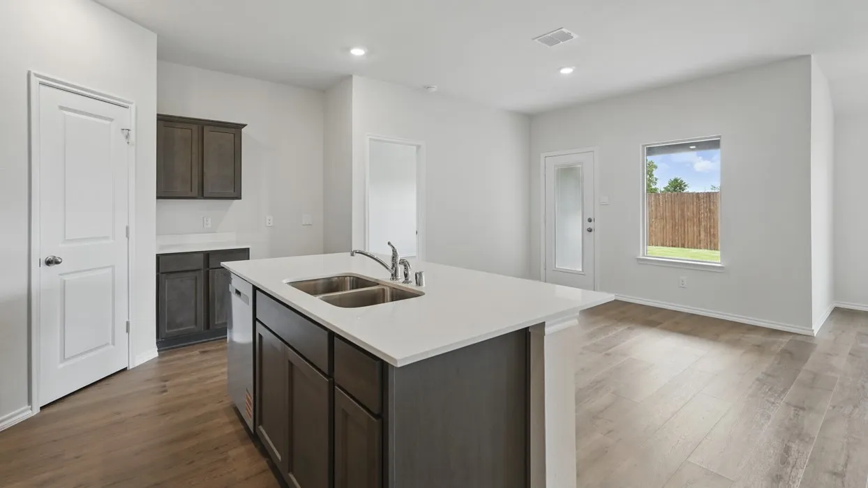 Kitchen island featuring an undermount double basin sink, stainless steel faucet, and white countertop