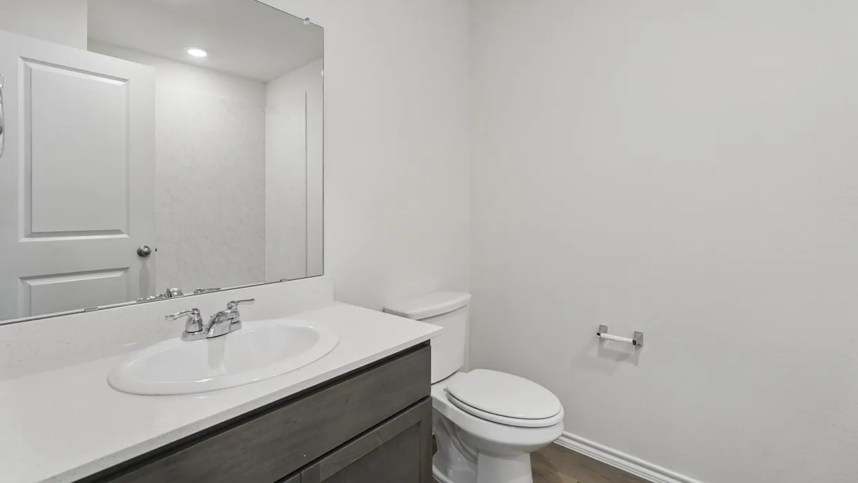 Vanity with a white countertop and integrated sink, chrome-finish faucet, and wood-finish cabinetry