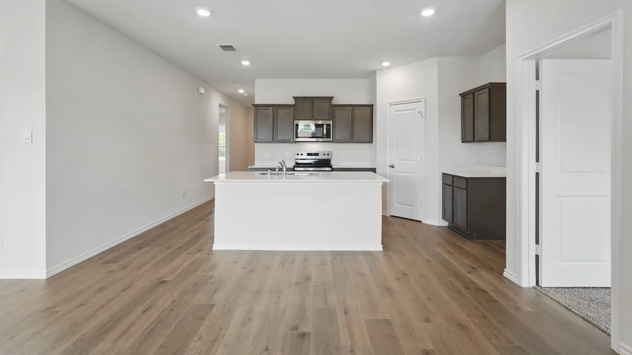 Kitchen featuring wood-finish flooring, recessed lighting, a kitchen island with sink, dark wood cabinetry, and a built-in microwave