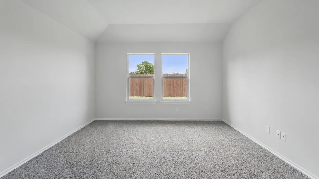 Neutral tone walls, grey textured carpeting, two windows, and a vaulted ceiling