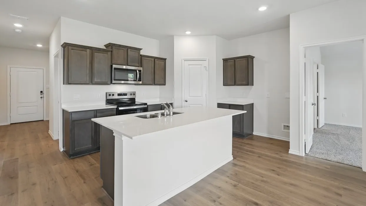 Kitchen featuring a center island with an undermount sink, dark wood-finish cabinetry, stainless steel appliances, and wood-finish flooring