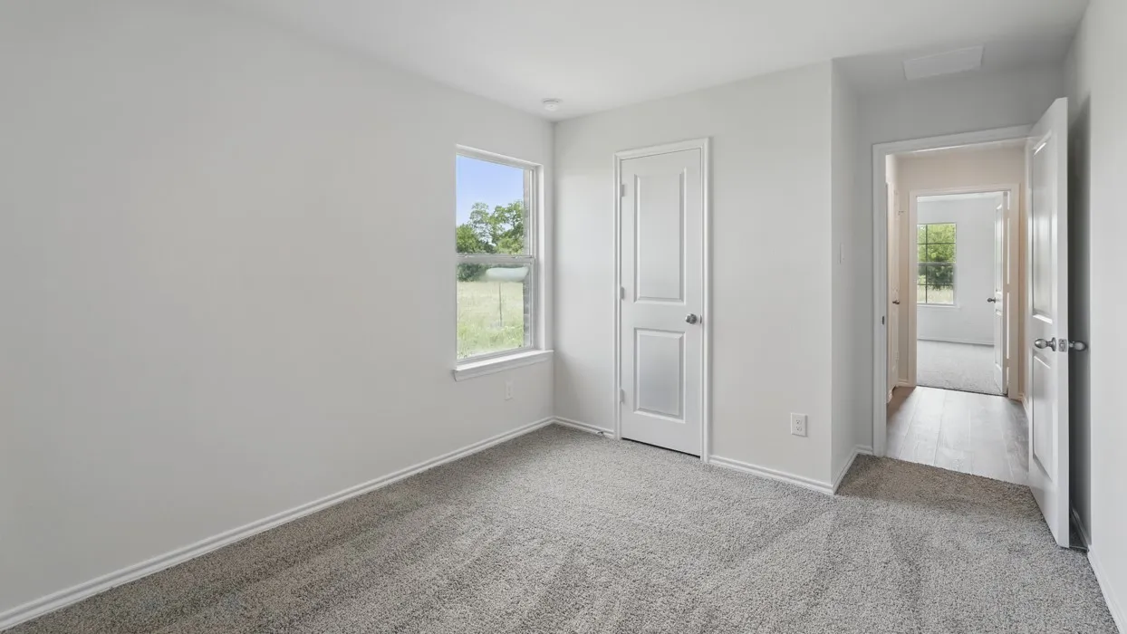 Neutral wall color, single pane window, light gray carpet, white interior door, wood-finish flooring in hallway