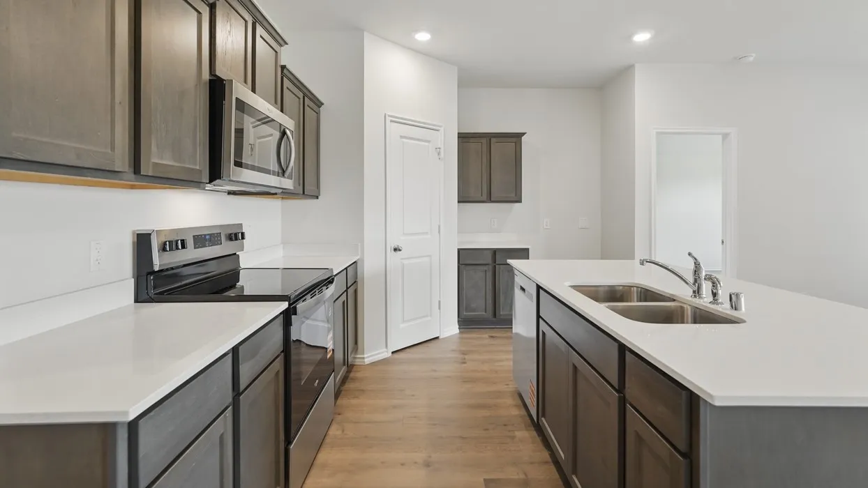 Kitchen featuring wood-finish flooring, dark wood cabinetry, white countertops, a stainless steel range, and a stainless steel microwave