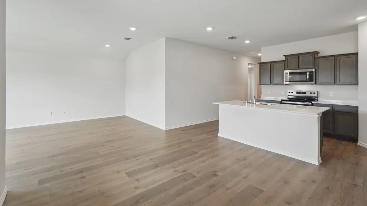 Wood-finish flooring throughout, recessed lighting, and a kitchen island with sink