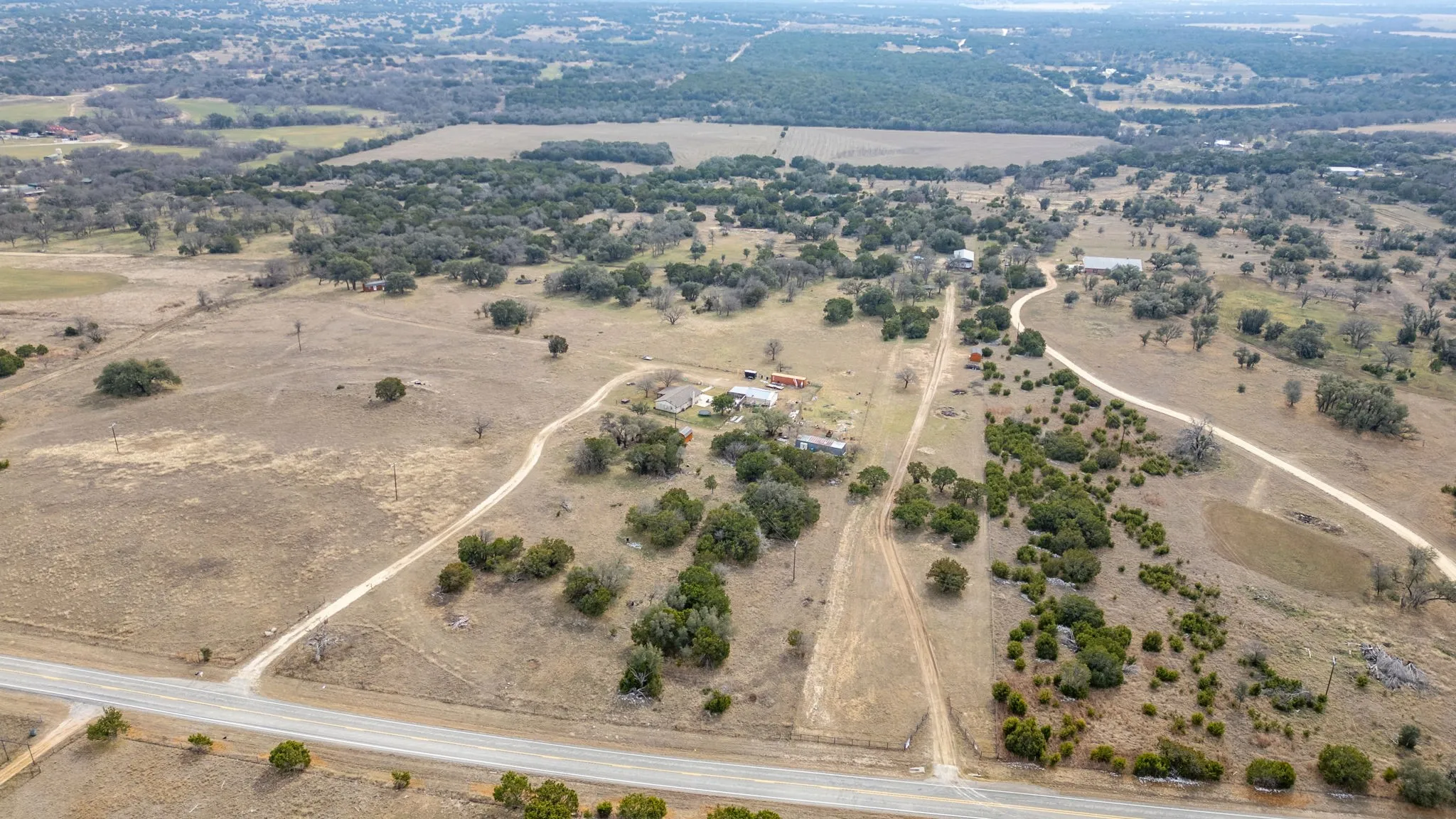 Expansive rural property featuring multiple structures and natural landscaping with scattered trees