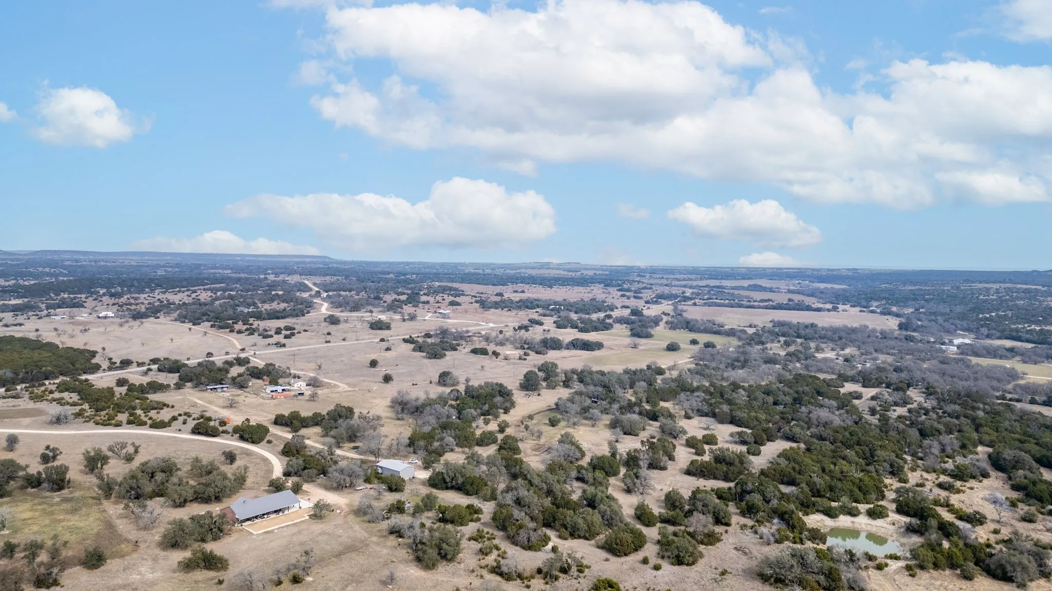 Expansive rural landscape featuring scattered trees and a natural water feature