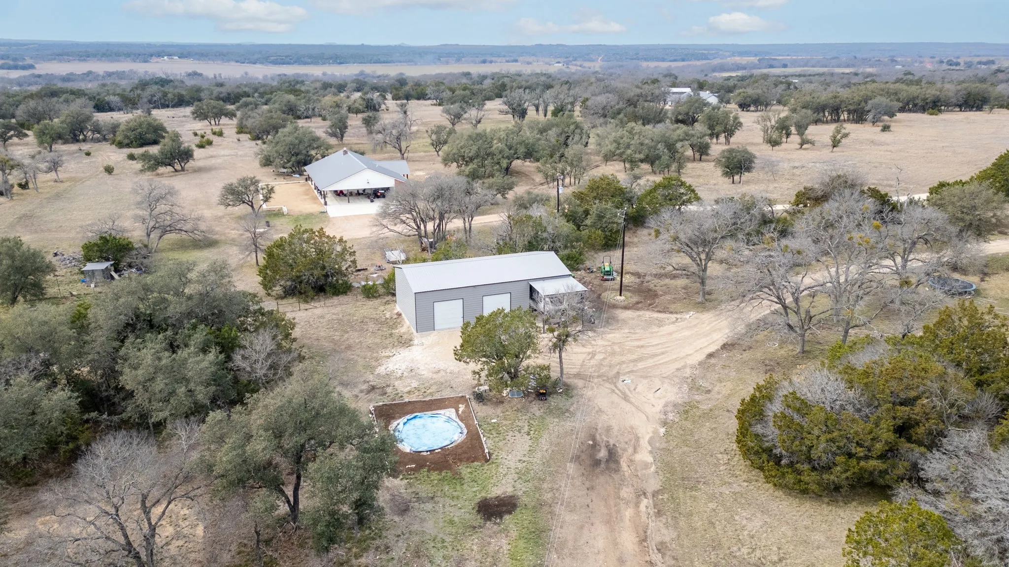 Aerial view showcasing a modern residence with clean architectural lines situated on expansive acreage