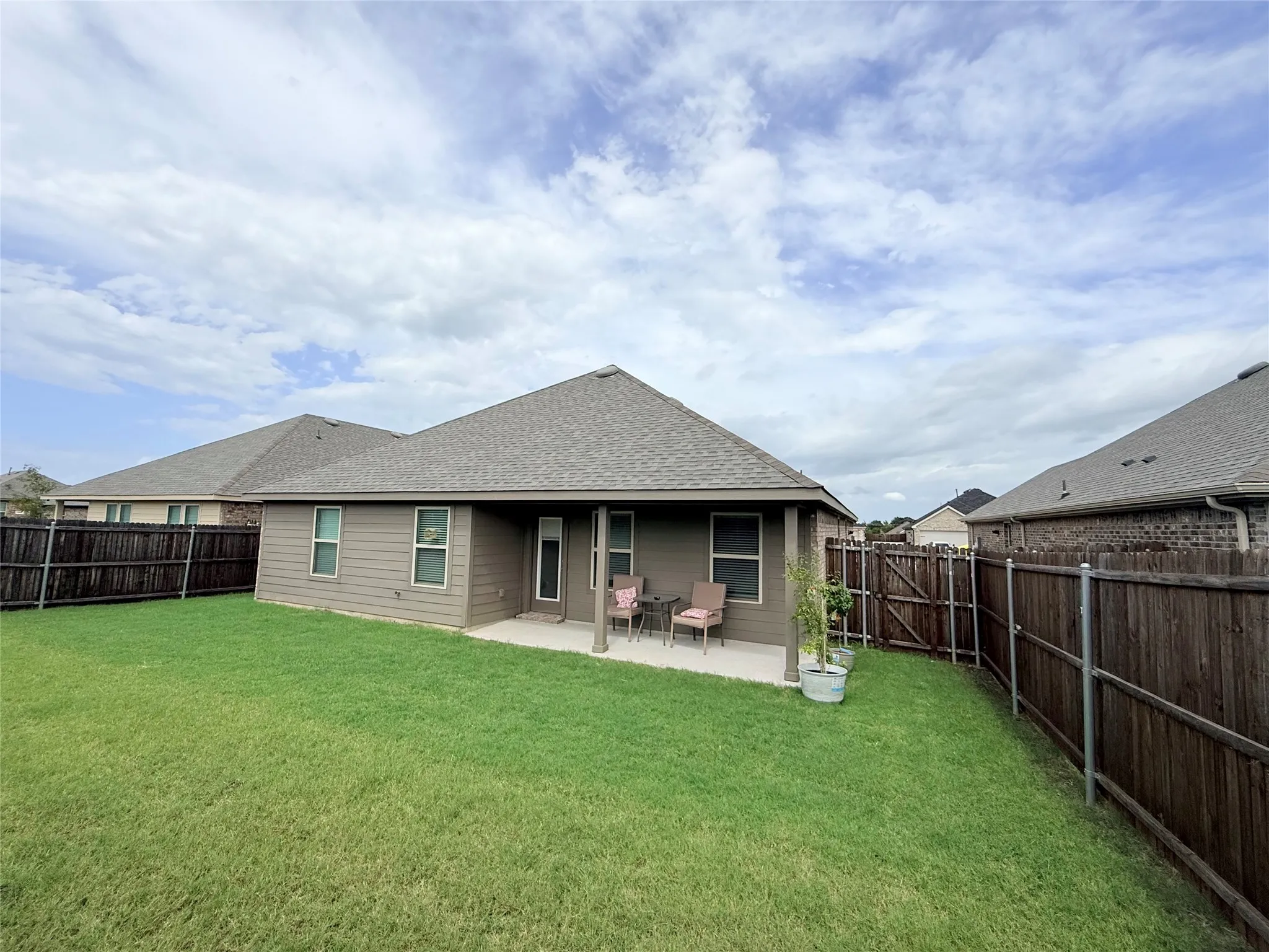 Expansive backyard featuring a manicured lawn, full wood fencing, and a concrete patio