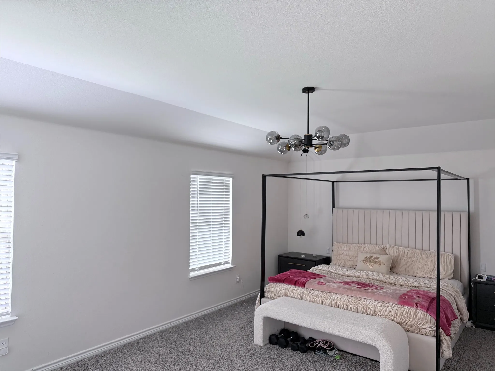 Recessed ceiling, dual windows with blinds, and a contemporary chandelier