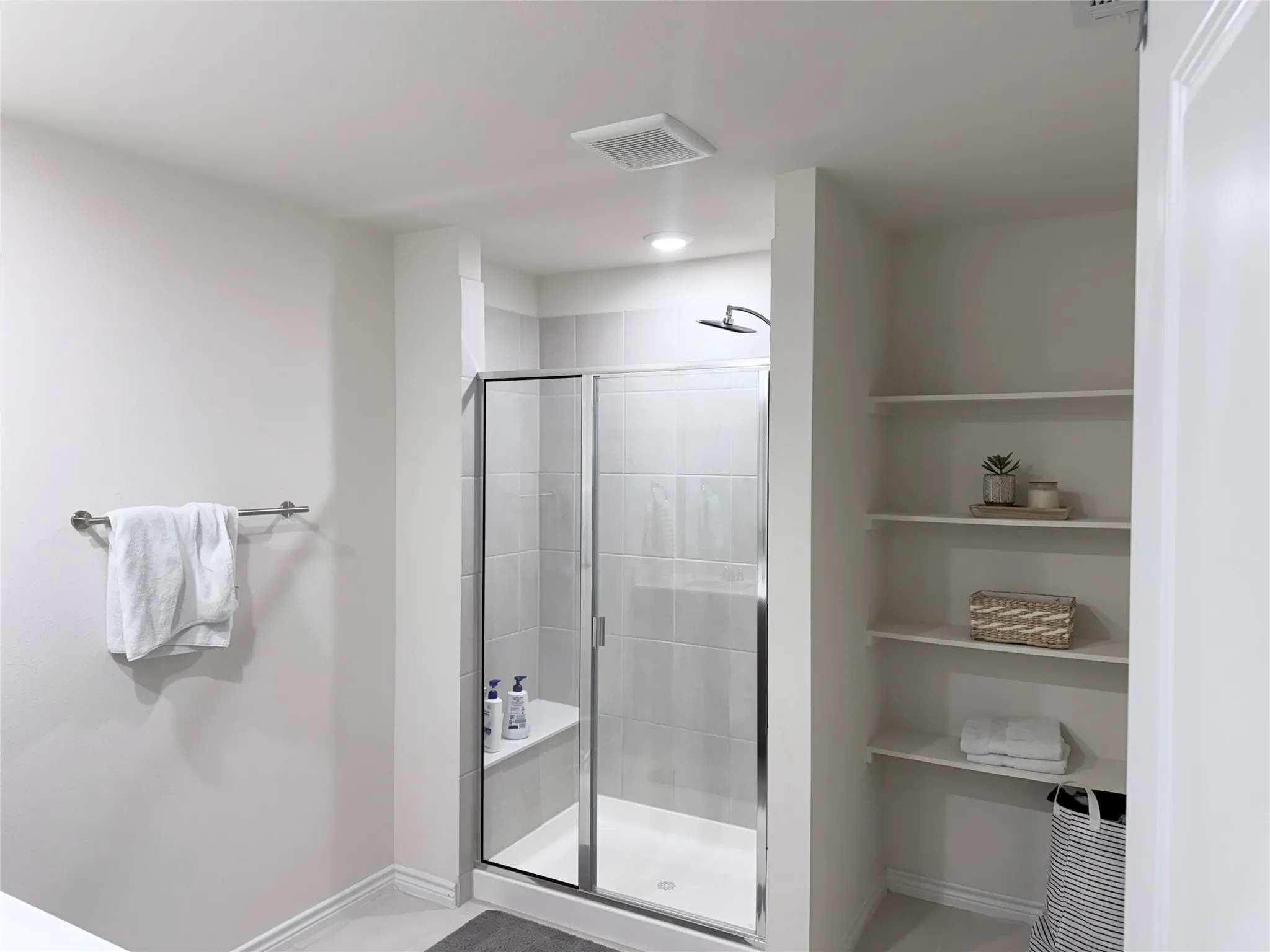 Enclosed shower with a built-in bench, glass door, and tile surround
