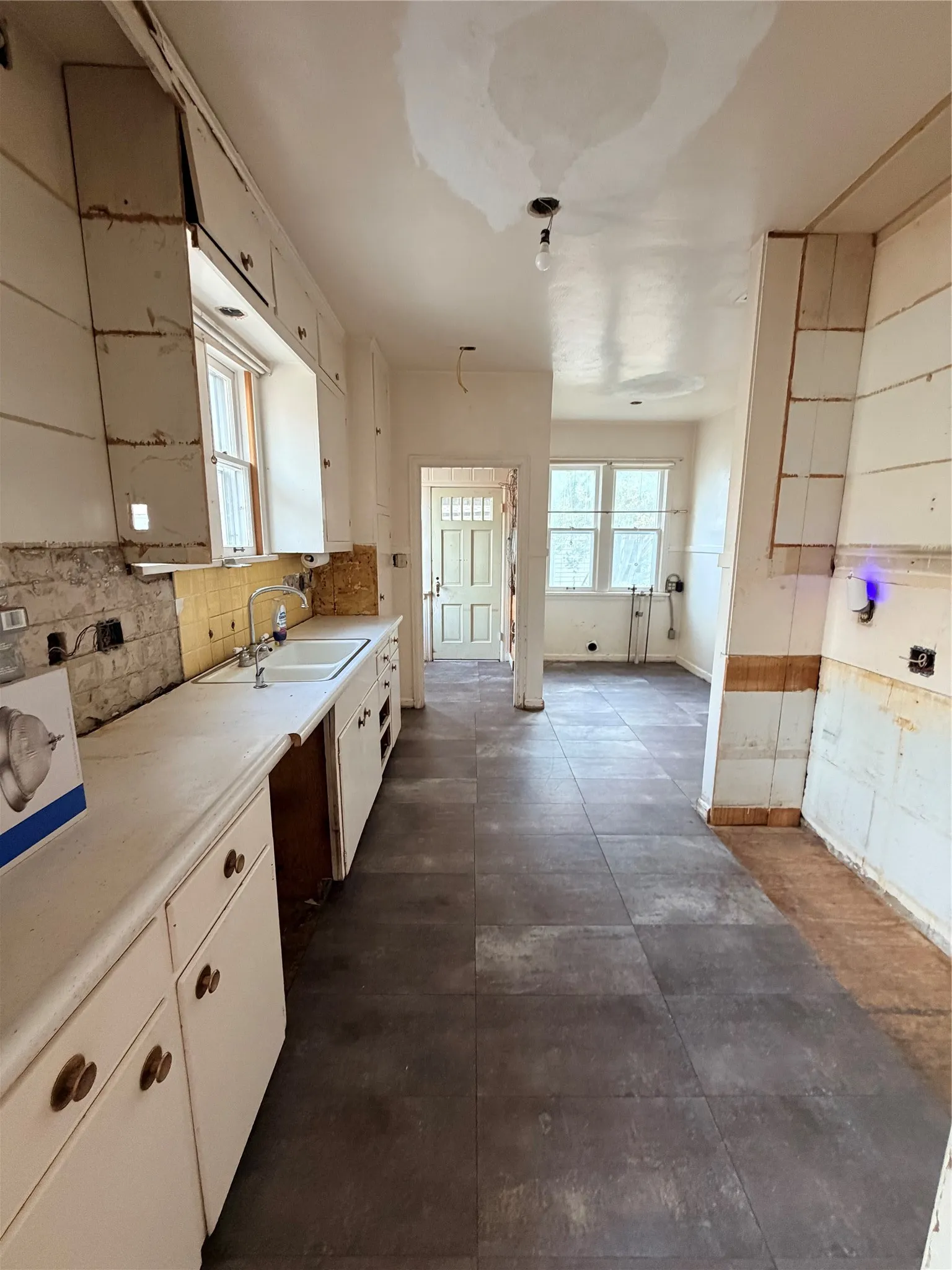 Kitchen featuring white cabinetry, a double basin sink, and dark-toned floor tiling